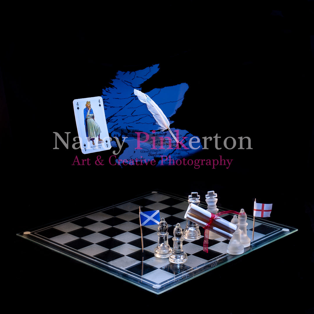 Photographic art print with image of a playing card featuring King Alexander the II, a graphic of map of Scotland and a quill floating above a chessboard with the flags of Scotland and England either side of two king pieces holding a scroll.
