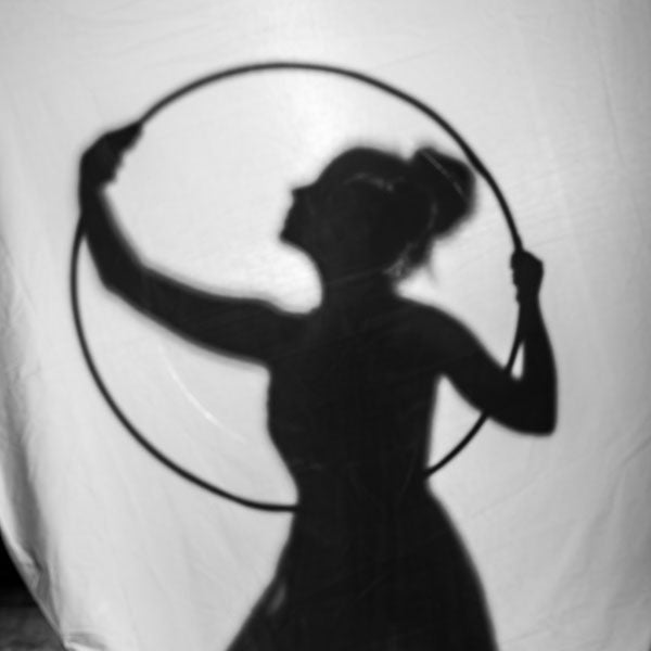 Black silhouette of a person with hoop behind a white curtain