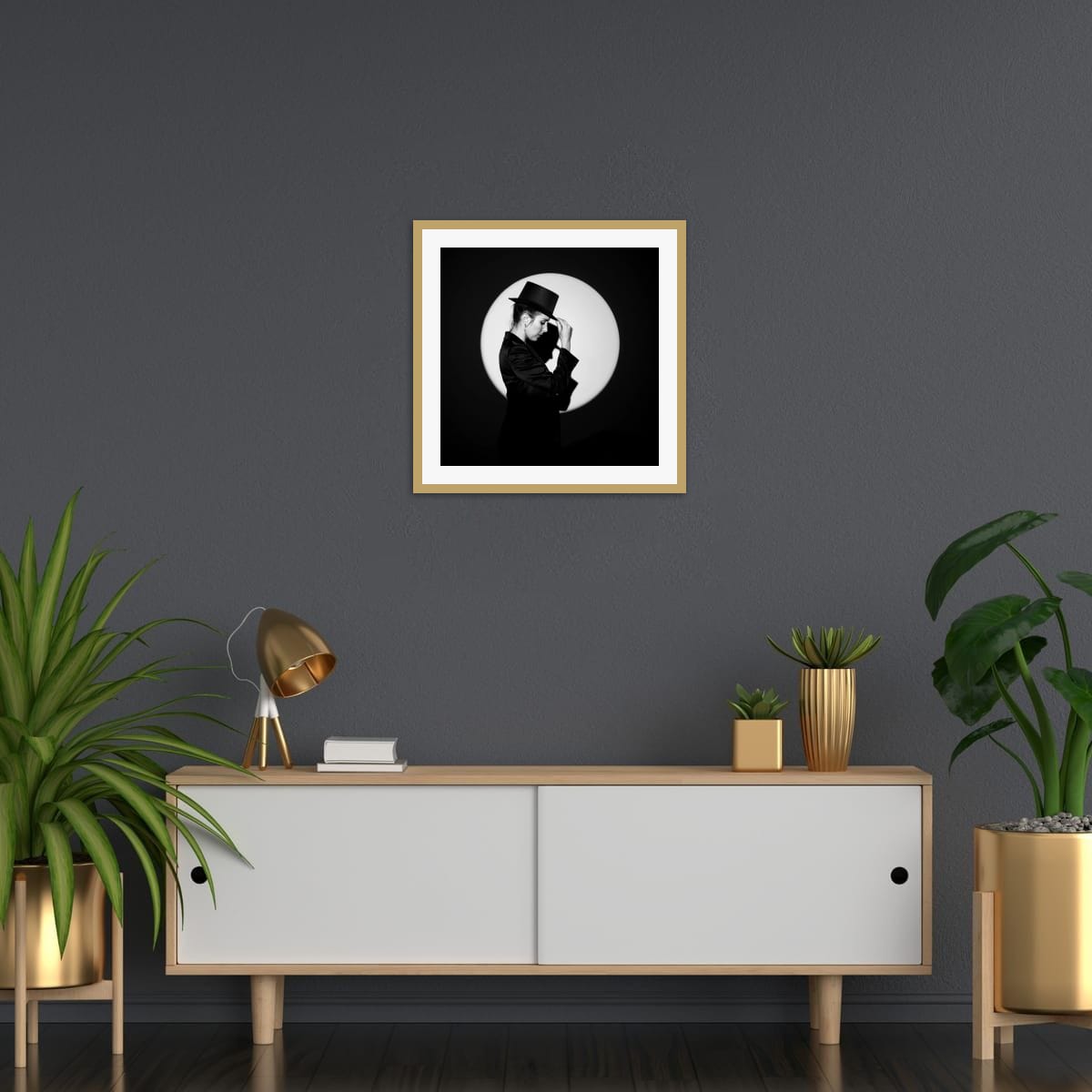 Framed black and white artwork 'In the Spotlight' above a wooden console table with decorative items against a dark wall.