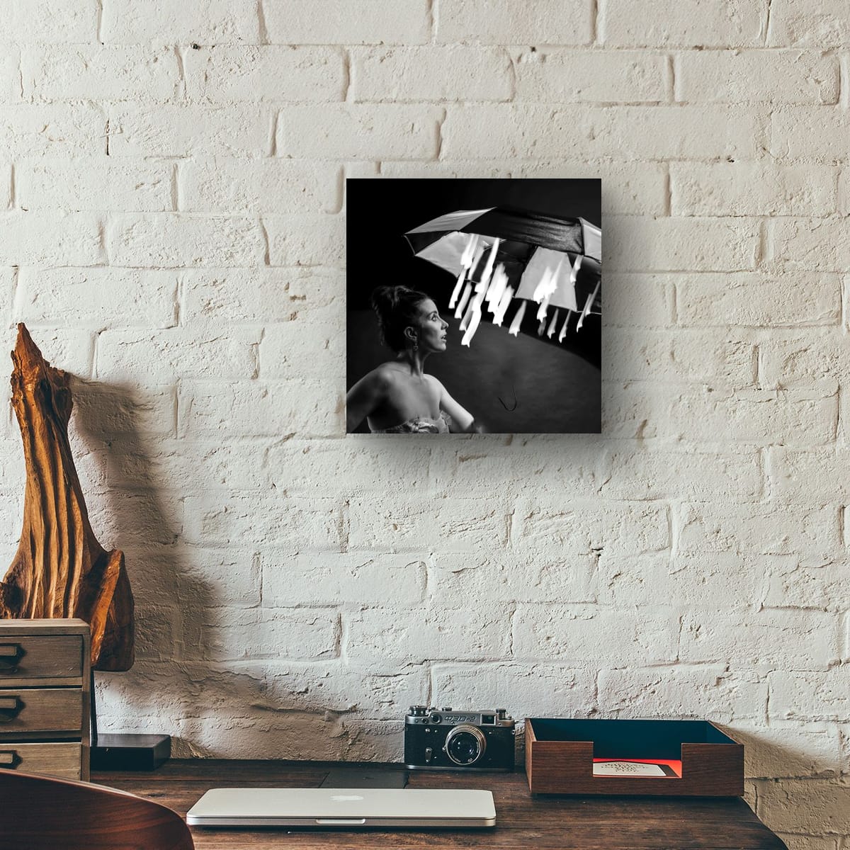 Framed black and white photograph Magical starlight on a brick wall above a desk with a camera and other items.