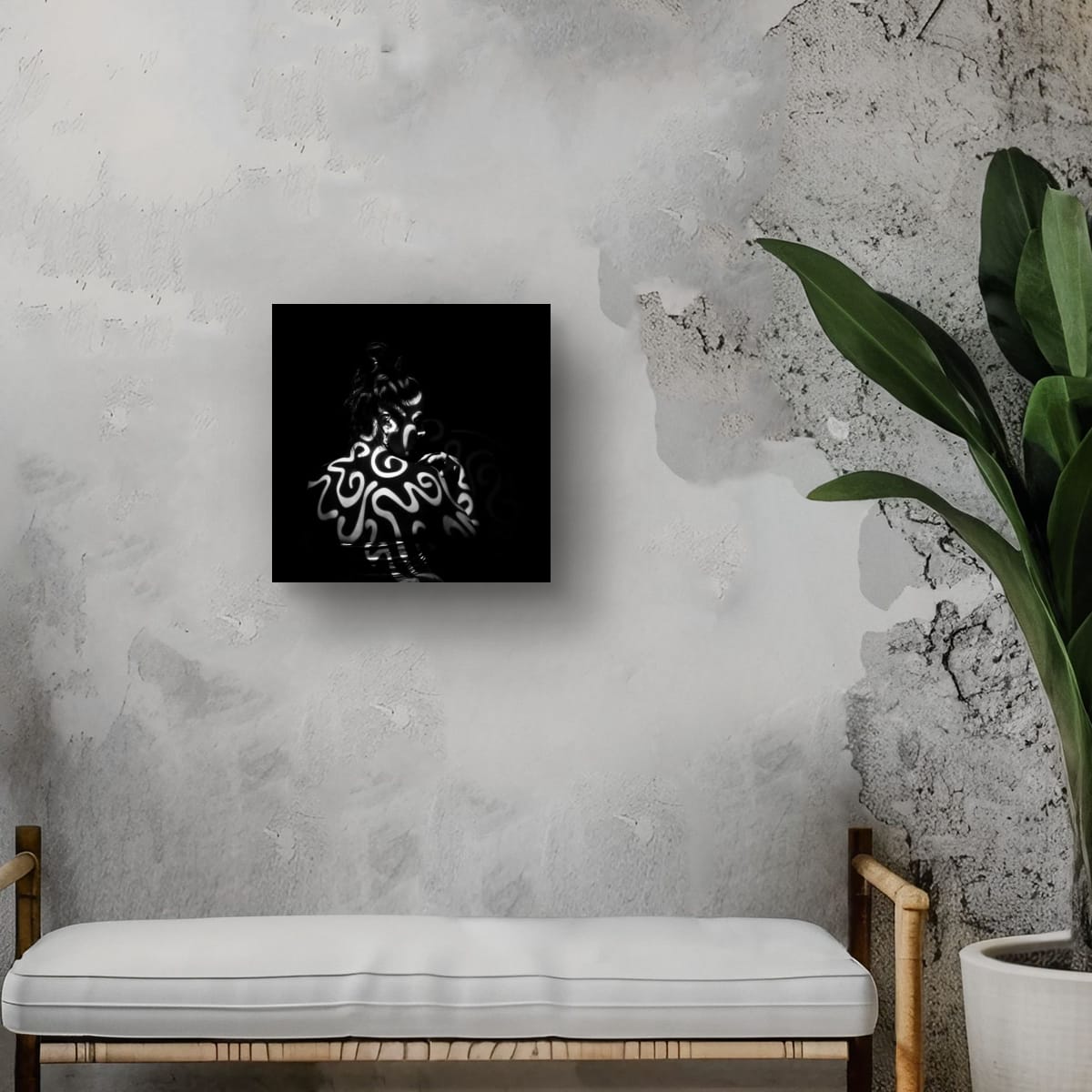 Black and white  artwork Tattoed with light on a gray wall with a bench and plant