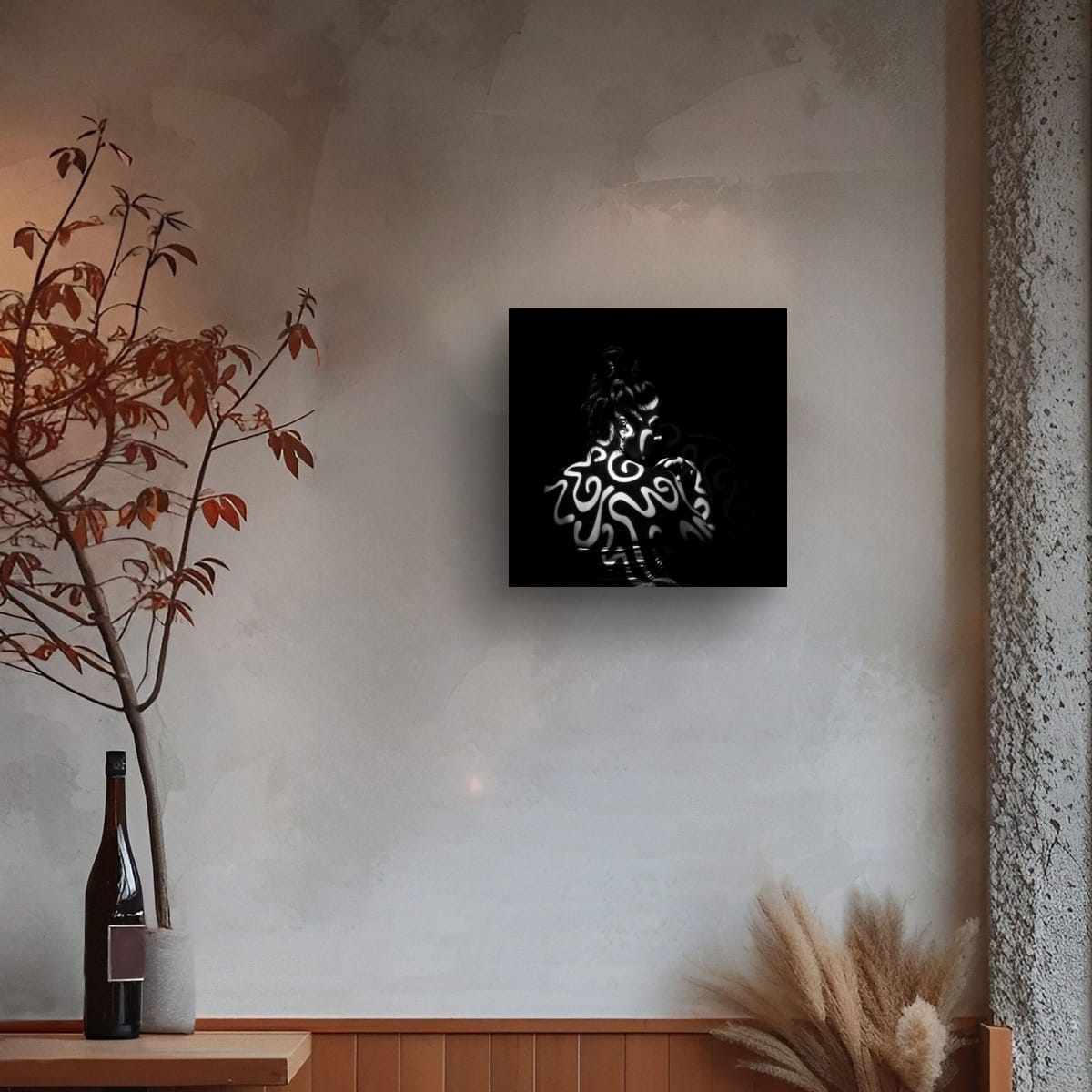 Decorative wall art Tattooed by light on a textured wall, next to a vase with branches and a bottle.